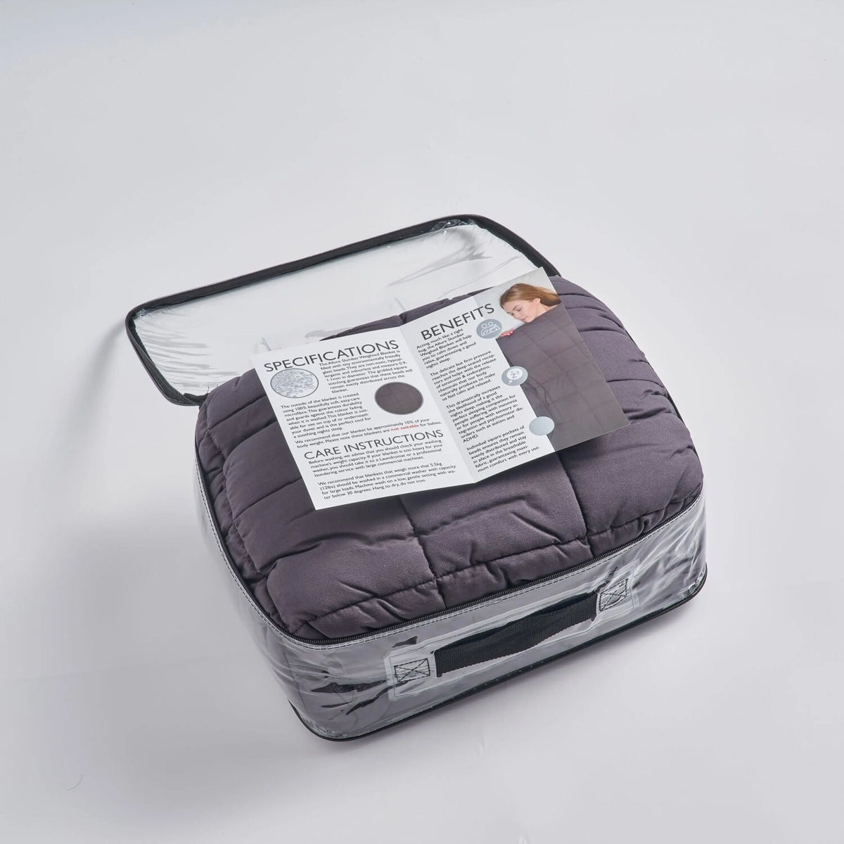 Couverture lestée Slumber gris anthracite pliée dans son sac de rangement transparent avec sa notice.
