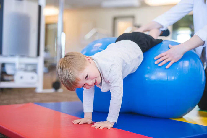 enfant avec un ballon géant de stimulation vestibulaire