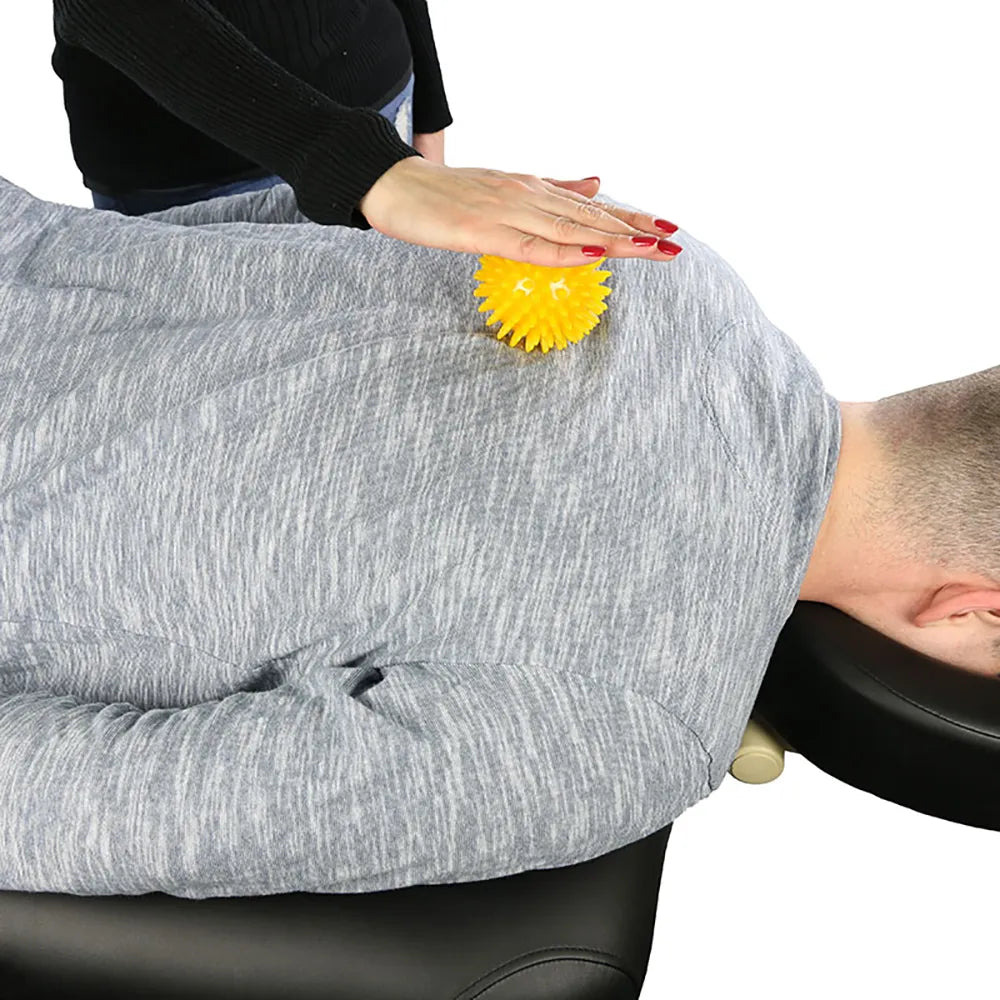 Massage du dos avec une petite balle sensorielle jaune de 8 cm à picots.