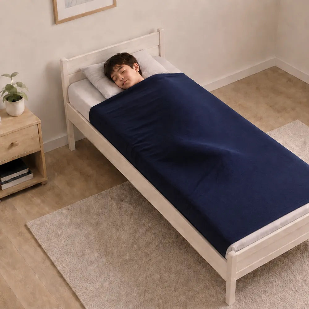 Enfant allongé sous un drap de compression bleu sur un lit une place