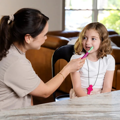 Utilisation de l’embout de massage vert sur un Z‑Vibe lors d’un exercice de stimulation orale avec une enfant.