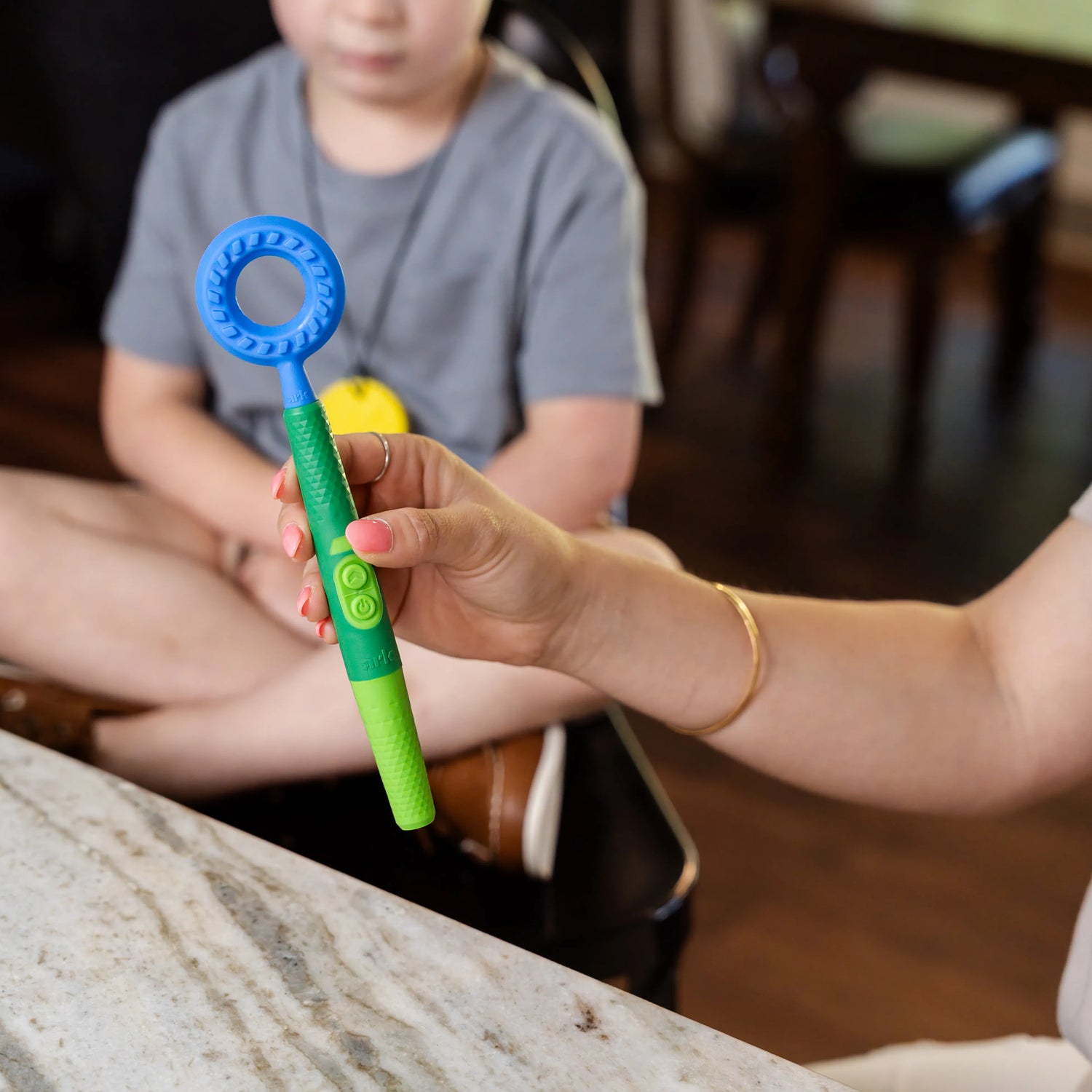 Embout rond bleu ARK monté sur un Z‑Vibe vert et présenté devant un enfant.