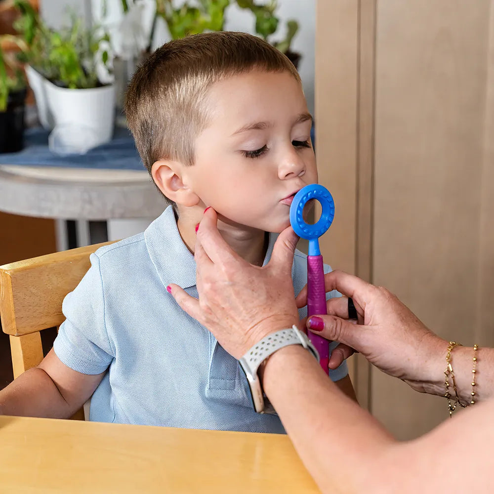 Utilisation de l’embout rond bleu ARK sur un Z‑Vibe pour stimuler le contour des lèvres chez un enfant.