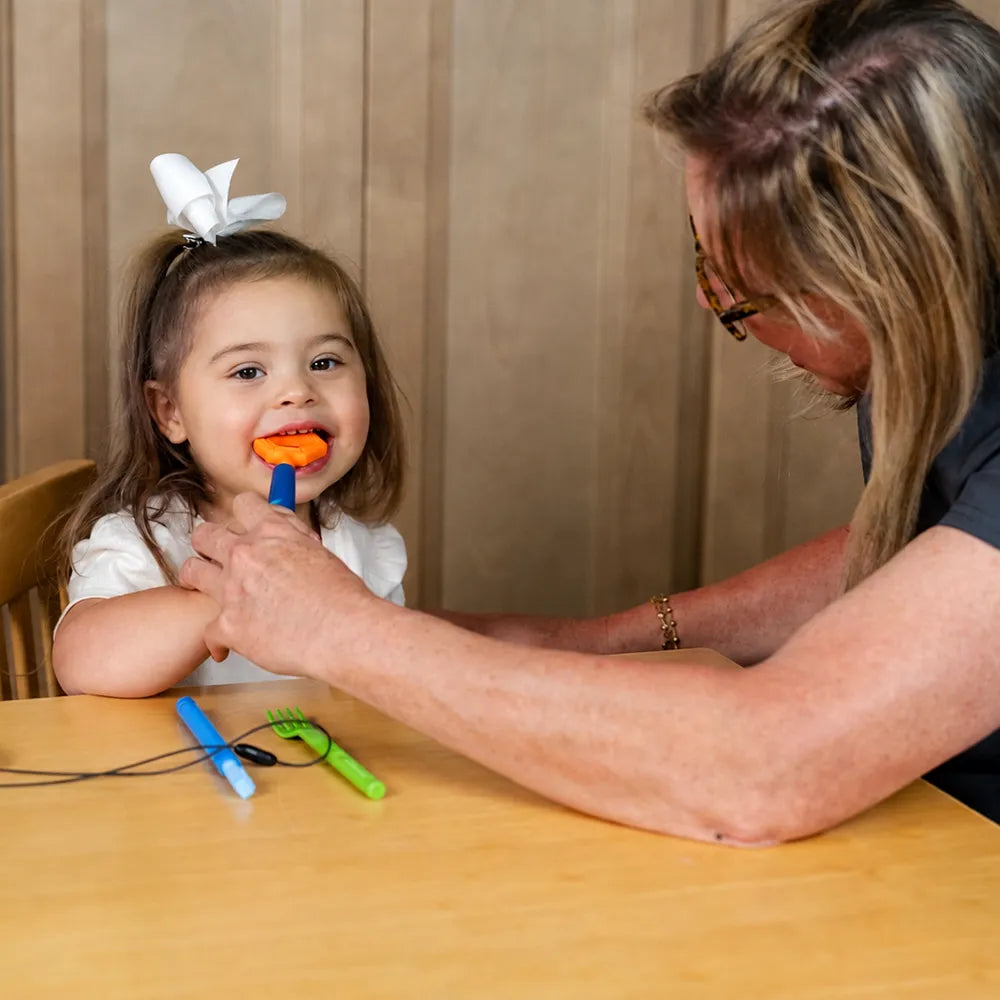 Utilisation de l’embout hexagonal orange sur un Z‑Vibe lors d’un exercice de stimulation orale avec une enfant.