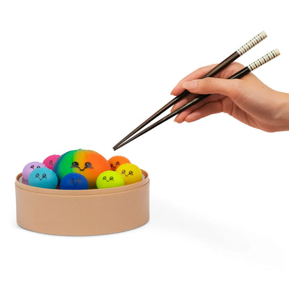 Main tenant des baguettes au-dessus du panier vapeur rempli de squishies colorés