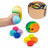 Main pressant un squishy multicolore, avec panier vapeur et huit petits squishies antistress colorés.
